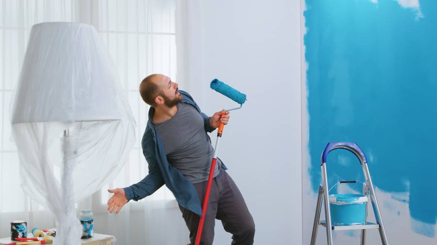 happy-repairman-singing-roller-brush-home-renovation-painting-with-blue-paint-apartment-redecoration