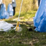 Activist using claw tool collect rubbish plastic junk from ground