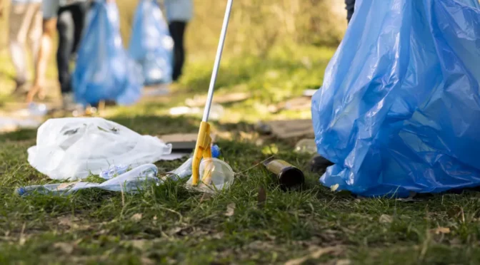 Activist using claw tool collect rubbish plastic junk from ground