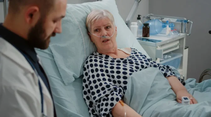 Close up elder patient laying bed talking medic healthcare treatment doctor consulting sick woman with nasal oxygen tube iv drip bag recovery hospital ward