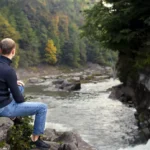 Full shot man sitting rock
