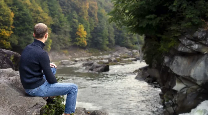 Full shot man sitting rock