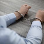 Selective focus shot male hands handcuffs wooden table