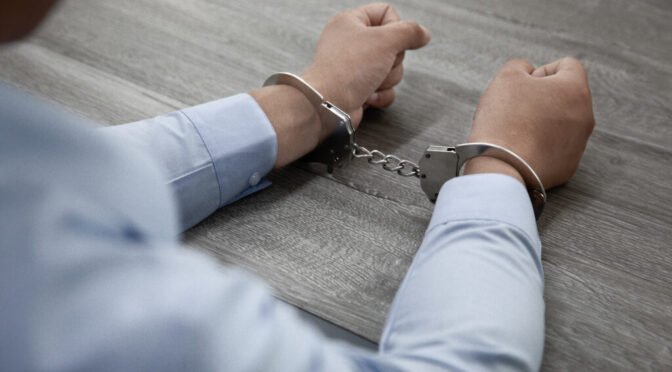 Selective focus shot male hands handcuffs wooden table